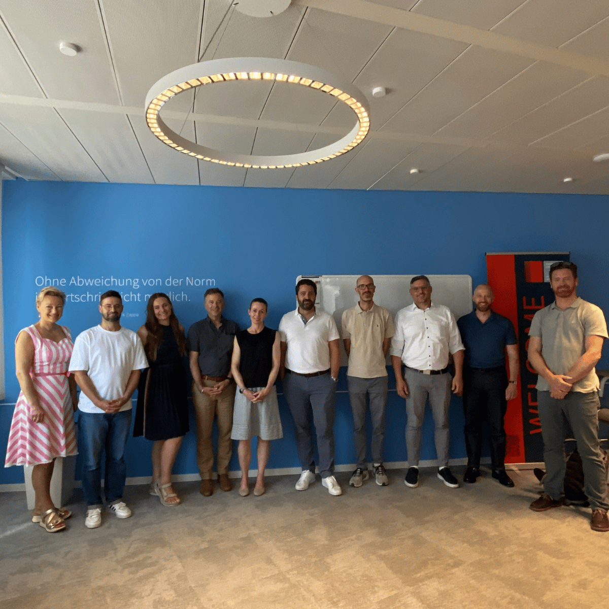 Group of people standing in front of a blue wall within a conference room